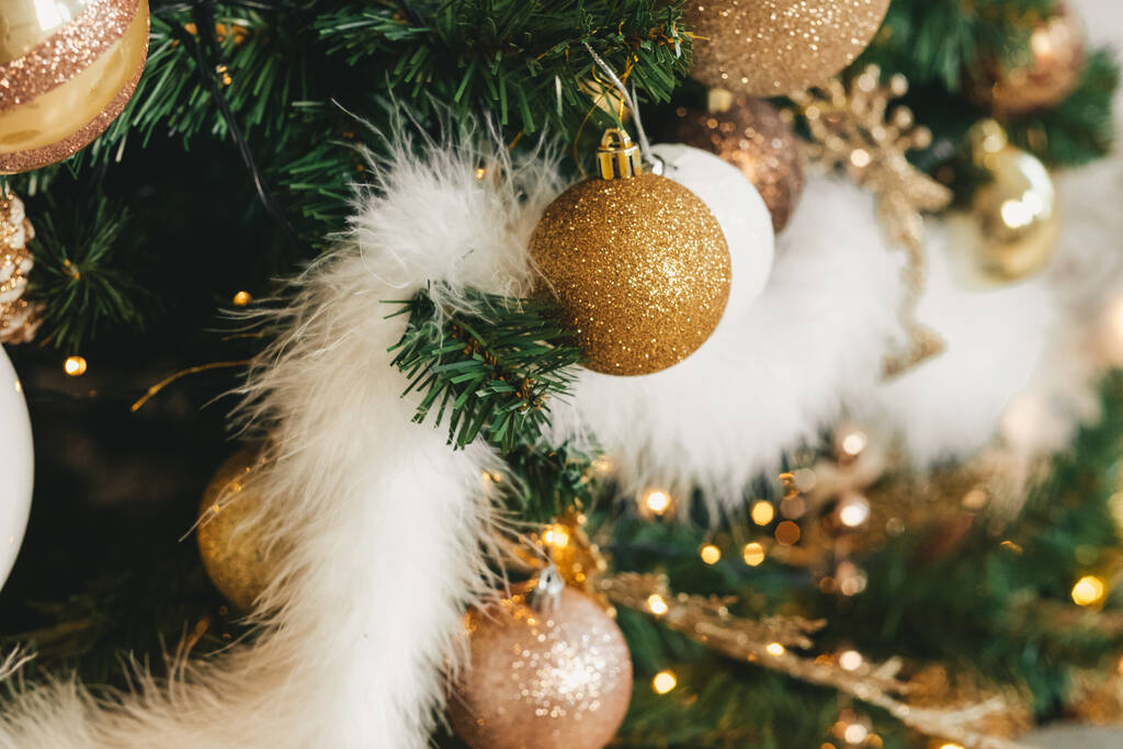 Χριστουγεννιάτικη χρυσή μπάλα σε ένα κοντινό χριστουγεννιάτικο δέντρο. Λευκή χνουδωτή κορδέλα στο χριστουγεννιάτικο δέντρο - Φωτογραφία, εικόνα