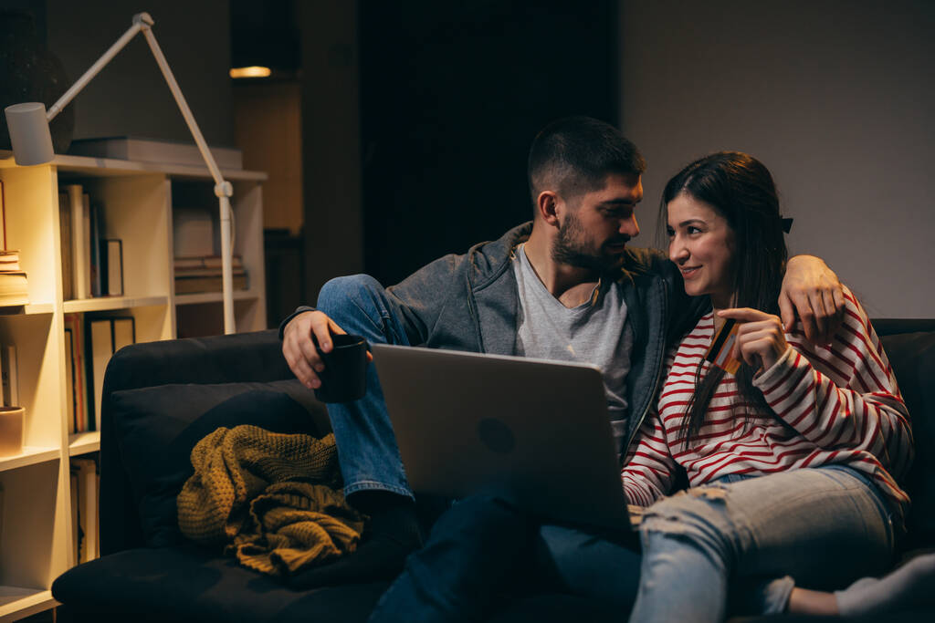 onnellinen nuori pari nauttii aikaa kotona kannettavan tietokoneen avulla - Valokuva, kuva