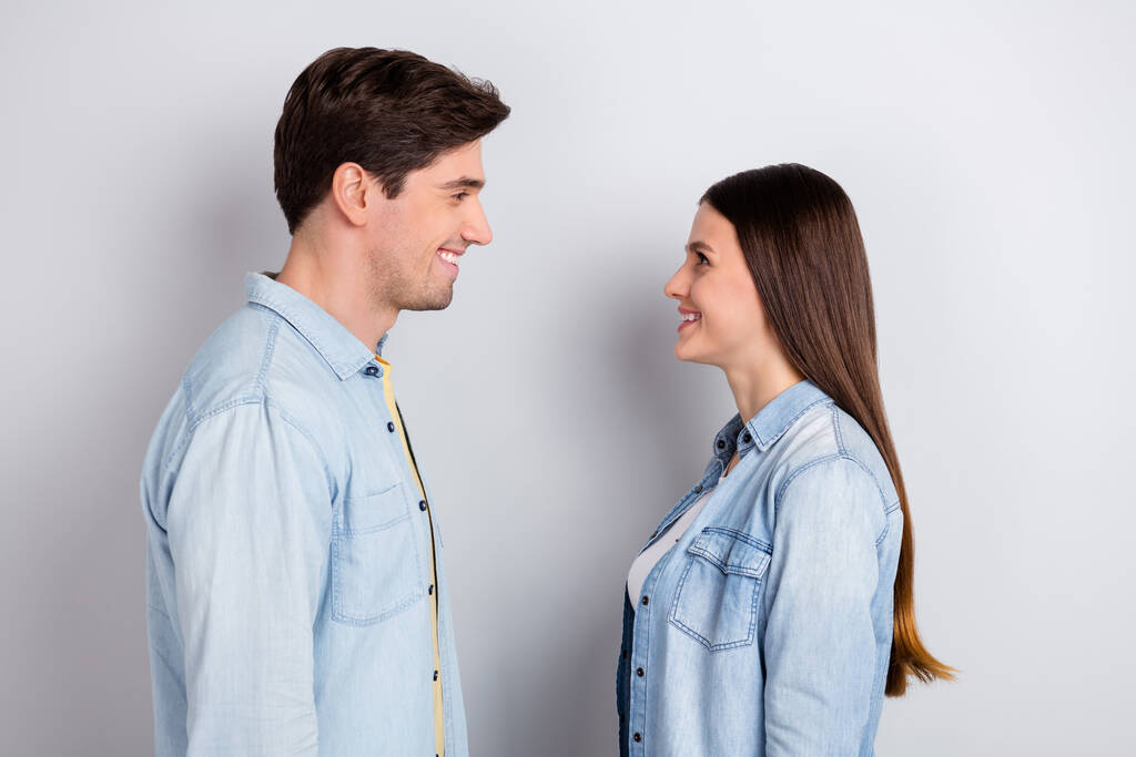 Фото милих симпатичних сестринських братів одягнених джинсових сорочок, що виглядають очима, посміхаючись ізольованому сірому кольоровому фоні
 - Фото, зображення