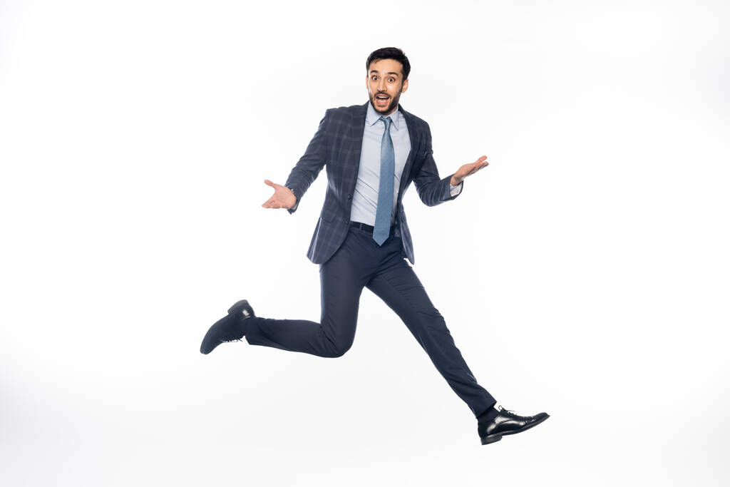 возбужденный бизнесмен в костюмах прыгает и жестикулирует на белом  - Фото, изображение