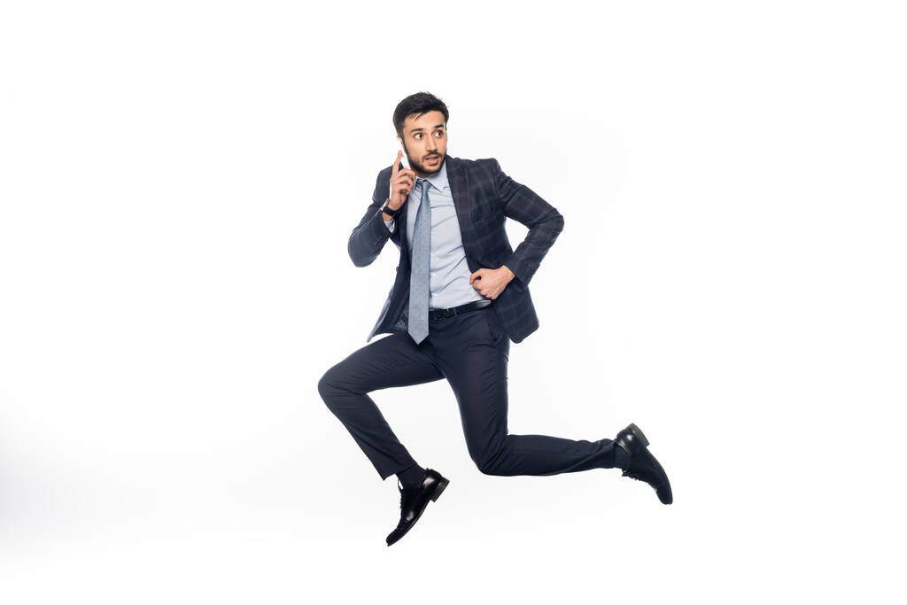 liikemies puku hyppääminen ja puhuminen älypuhelimella eristetty valkoinen  - Valokuva, kuva