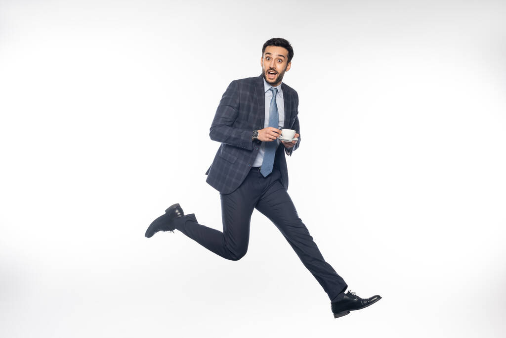 empresário animado em terno pulando com xícara de café em branco  - Foto, Imagem