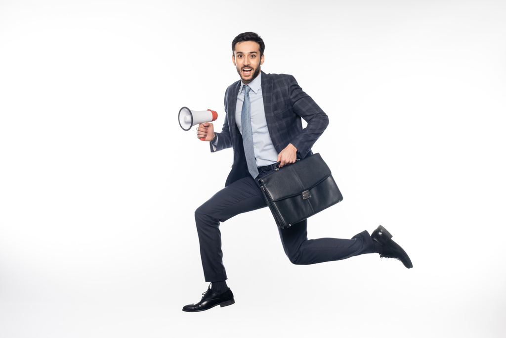 homem de negócios em terno pulando com alto-falante e pasta em branco  - Foto, Imagem