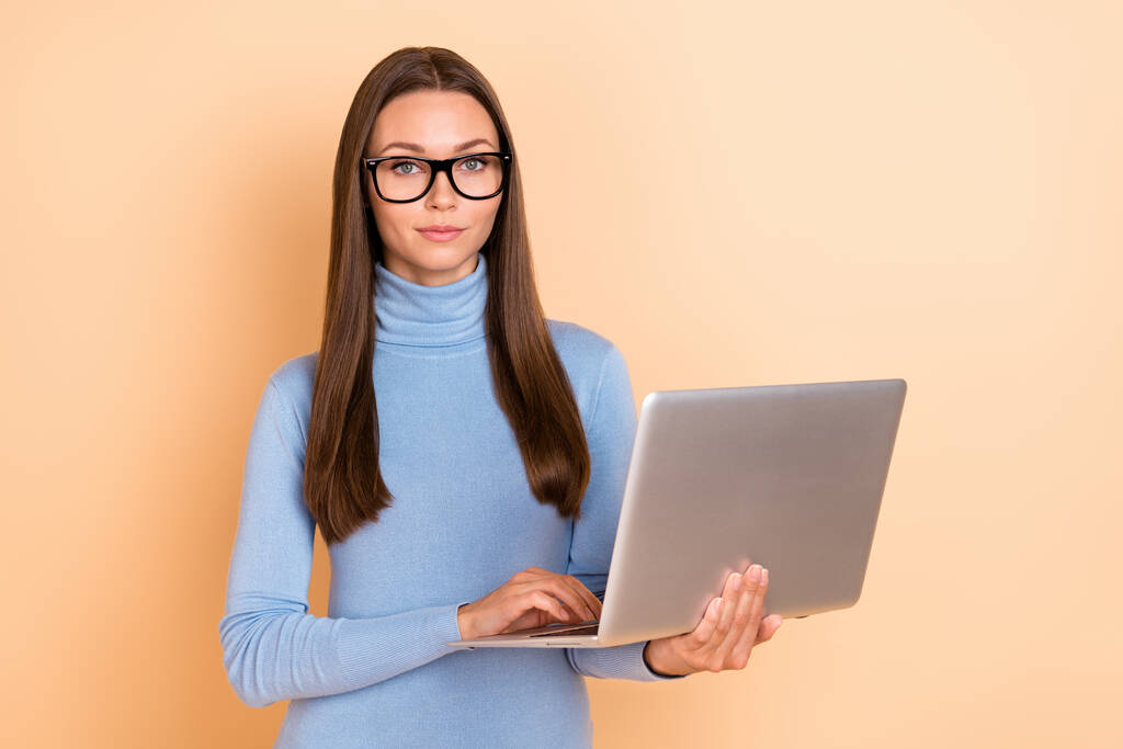 Foto van agent brunette jonge dame schrijven laptop dragen brillen blauwe trui geïsoleerd op beige kleur achtergrond - Foto, afbeelding