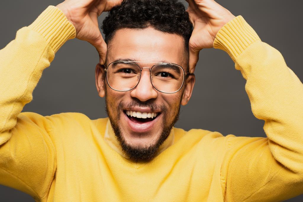 здивований афроамериканський чоловік в окулярах посміхається ізольовано на сірому
 - Фото, зображення