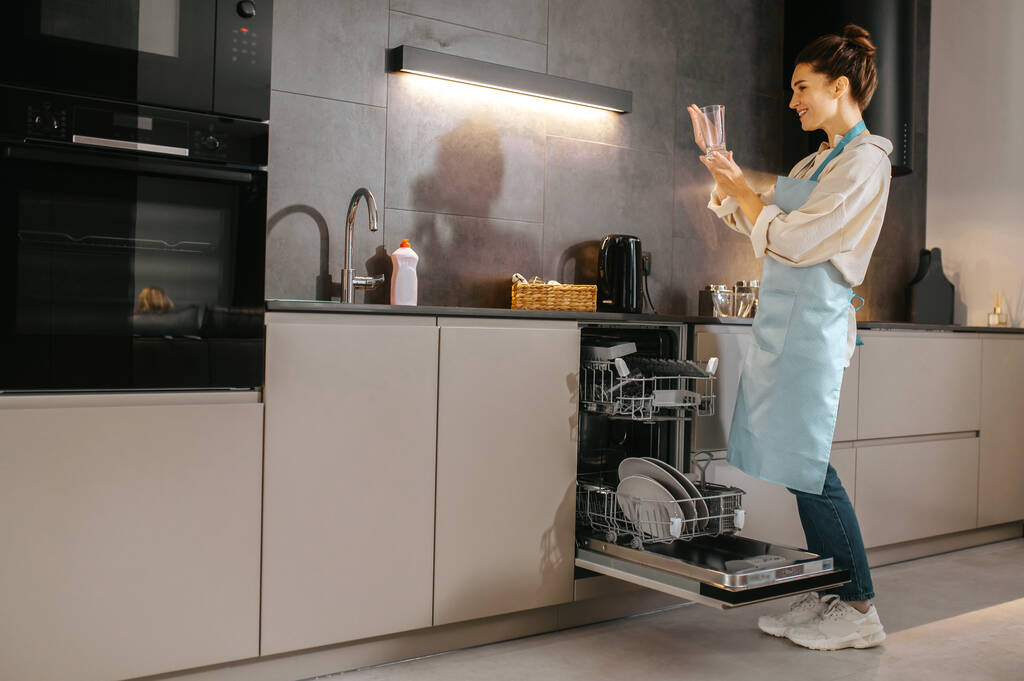 Nuori nainen keittiössä etsivät kiireinen pesemällä levyt - Valokuva, kuva