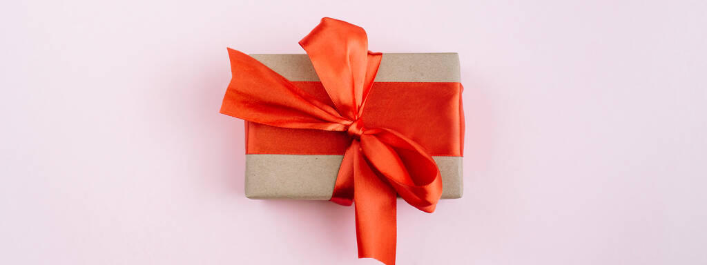 Banner made of Present box with red bow on pink background. Flat lay, top view, copy space - Photo, Image