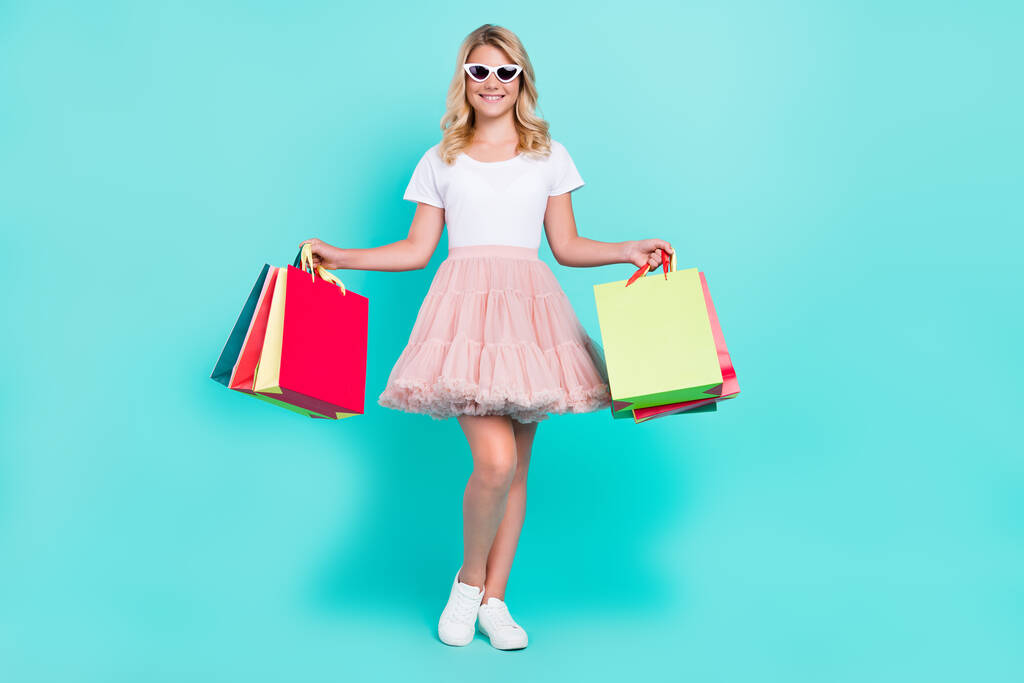 Photo de shopper dame magasin de détail porter des sacs lunettes de soleil blanc t-shirt jupe chaussures isolé aquamarine couleur fond - Photo, image