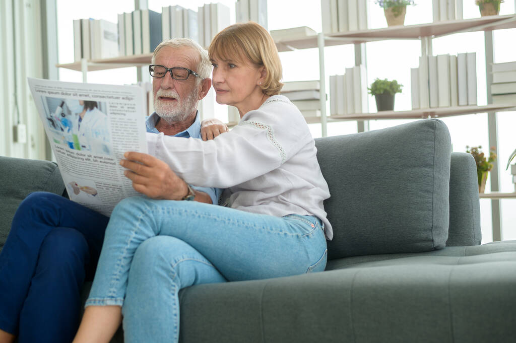 Happy Couple Caucasian senior are relaxing , reading newspaper in living room  - Photo, Image
