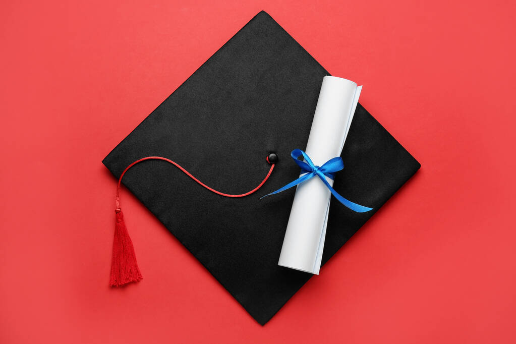 Graduation hat and diploma on red background, top view - Photo, Image