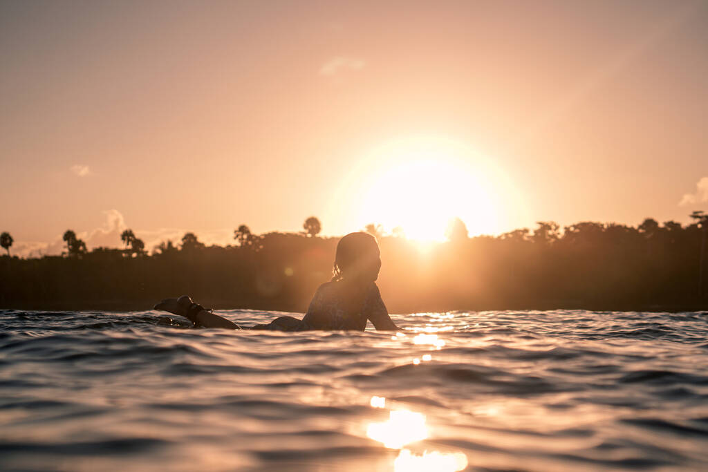 Портрет блондинки-серфингистки на белой доске для серфинга в голубом океане на золотом восходе солнца на пляже в Доминиканской Республике - Фото, изображение