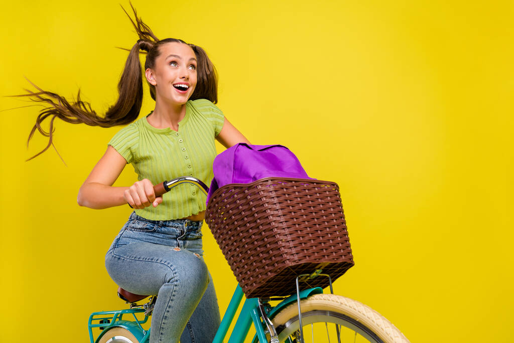 Πορτρέτο της ελκυστική girlish αστείο χαρούμενο κορίτσι ιππασία ποδήλατο διασκεδάζοντας απομονωμένη πάνω από φωτεινό κίτρινο χρώμα φόντο - Φωτογραφία, εικόνα