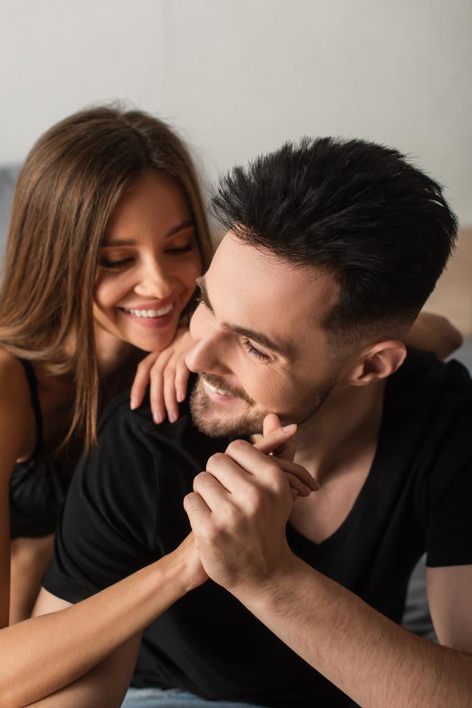 happy young couple holding hands and smiling in bedroom - Foto, Bild