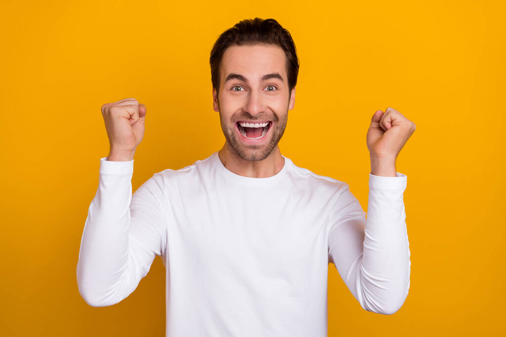 Porträt positiver ekstatischer Mann hebt die Fäuste schreien ja feiern erreichen isoliert auf gelbem Hintergrund - Foto, Bild