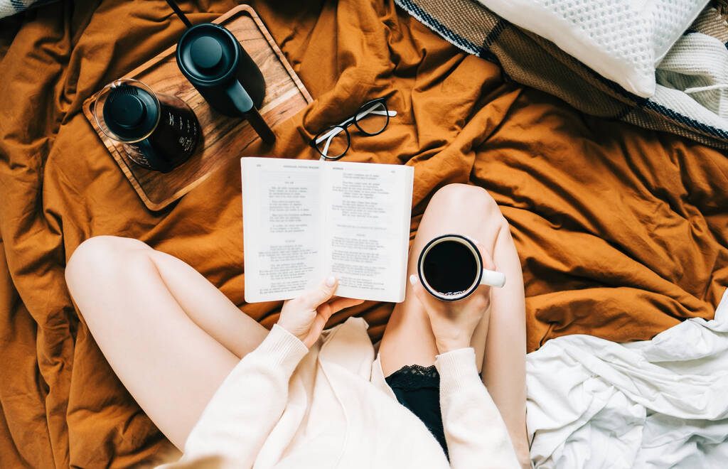 Mulher branca bebendo café pela manhã e lendo livro na cama em casa, aconchego e conceito de conforto. - Foto, Imagem
