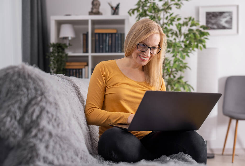 Woman sitting on sofa with laptop - Photo, Image