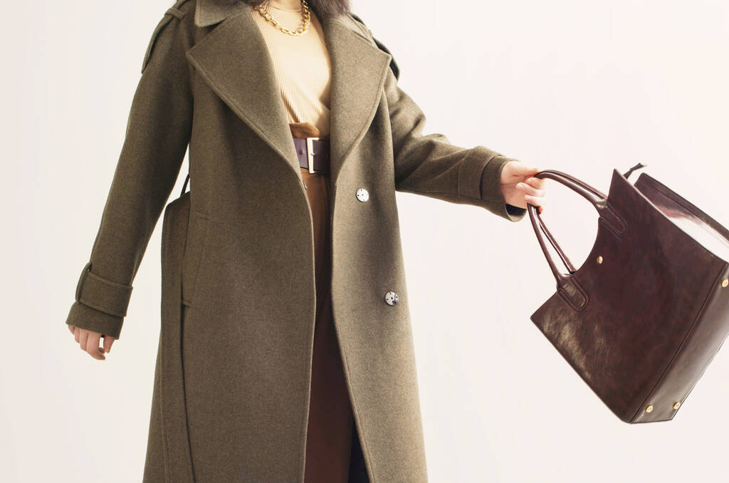 Güz ceketli genç bir kadın, beyaz arka planda el çantası var. - Fotoğraf, Görsel