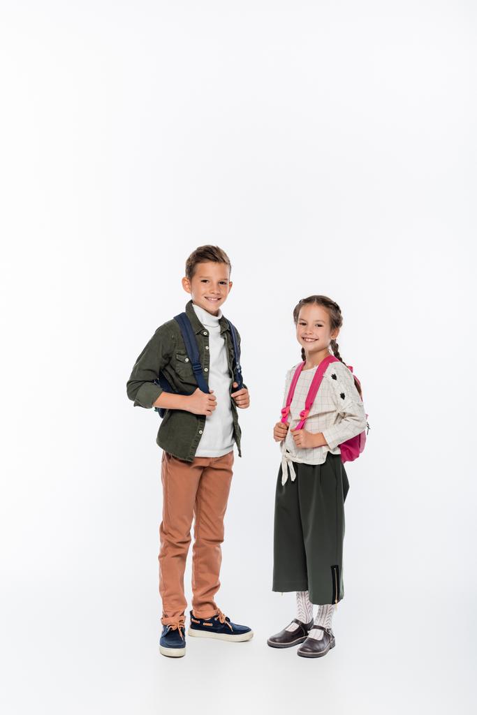 白いバックパックで立っている陽気な子供たち  - 写真・画像