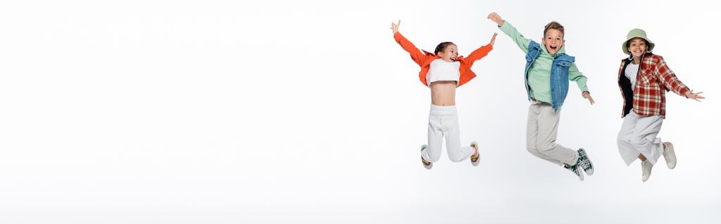 pełna długość stylowe dzieci uśmiechnięte podczas lewitacji na białym, baner - Zdjęcie, obraz