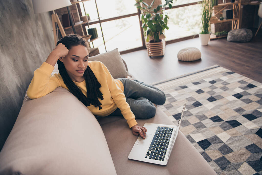 Çekici bir genç bayanın fotoğrafı sarı kazaklı koltukta oturmuş modern aletlerle evde çalışıyor. - Fotoğraf, Görsel