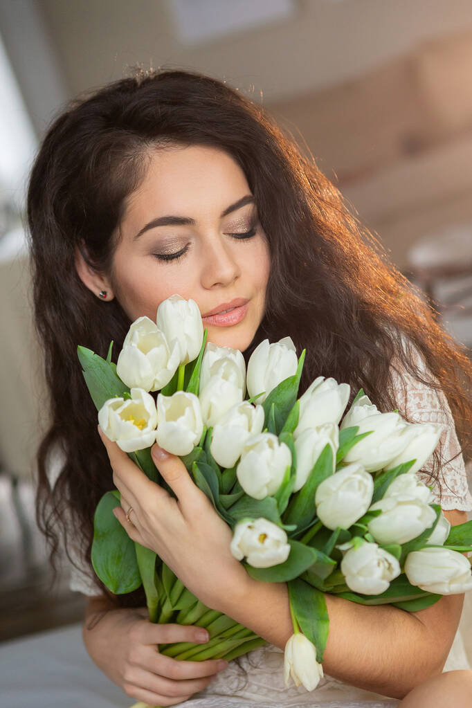 Egy gyönyörű fiatal nő portréja fehér tulipánokkal.. - Fotó, kép