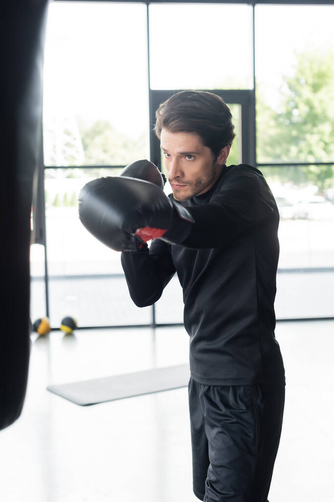 Boxeador morena haciendo ejercicio con saco de boxeo en el centro deportivo  - Foto, Imagen