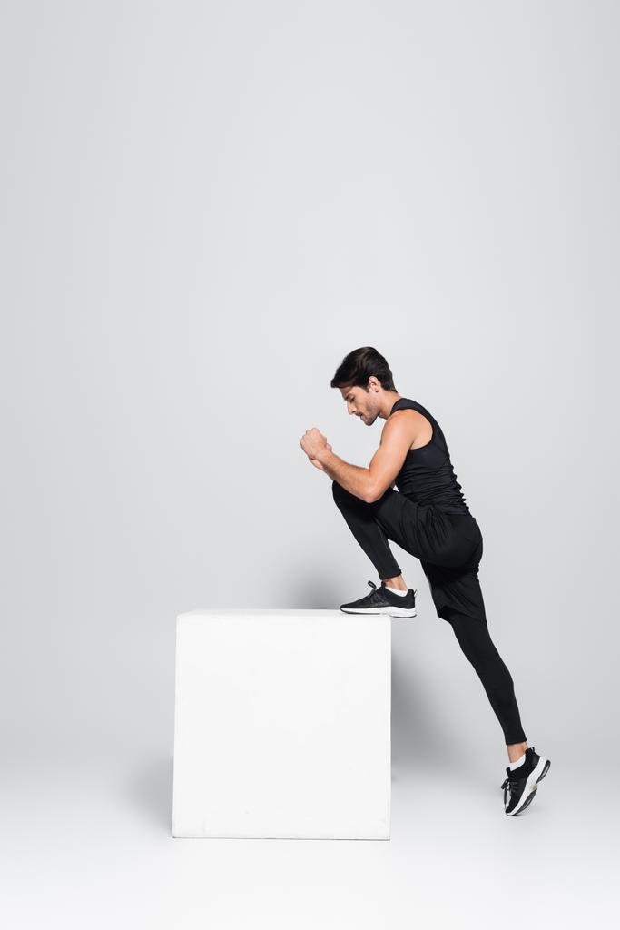 Side view of sportsman training with cube on grey background  - Photo, Image