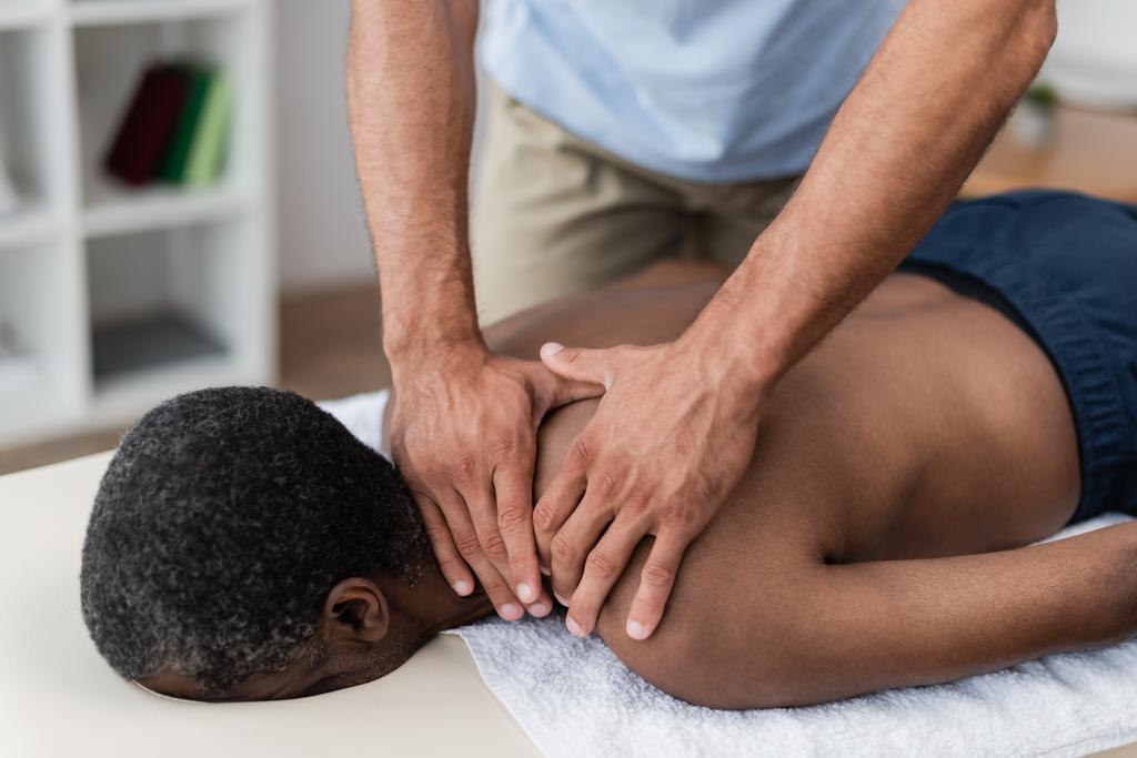 fyzioterapeut dělá masáž šíje a ramen zralému Afroameričanovi - Fotografie, Obrázek