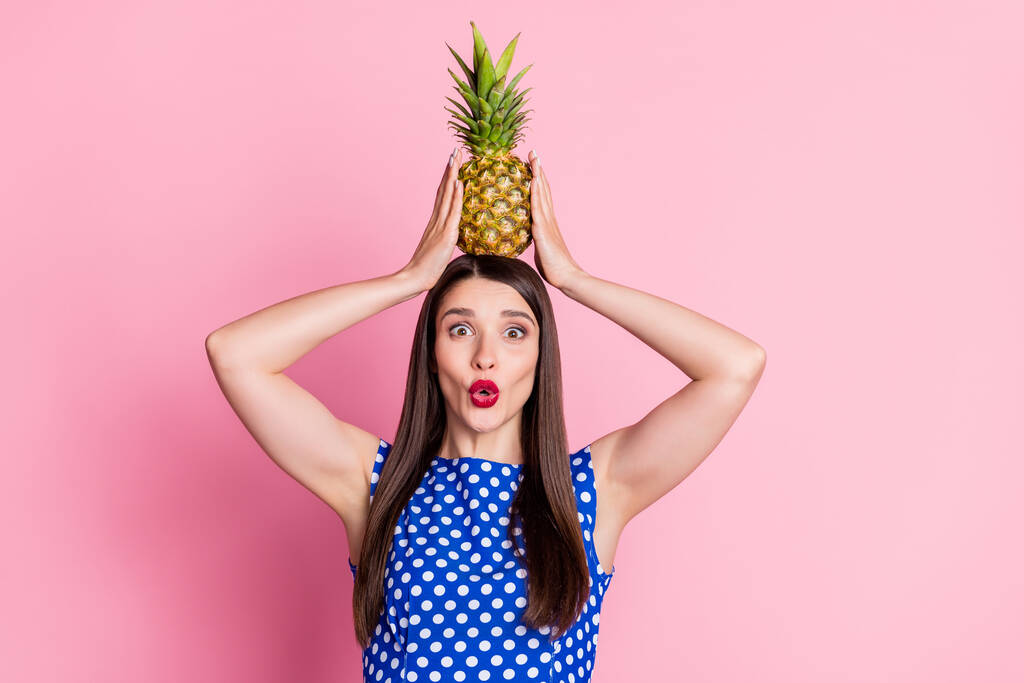 Portrét atraktivní veselá legrační dívka drží ananas na hlavě našpulené rty izolované přes růžové pastelové barvy pozadí - Fotografie, Obrázek
