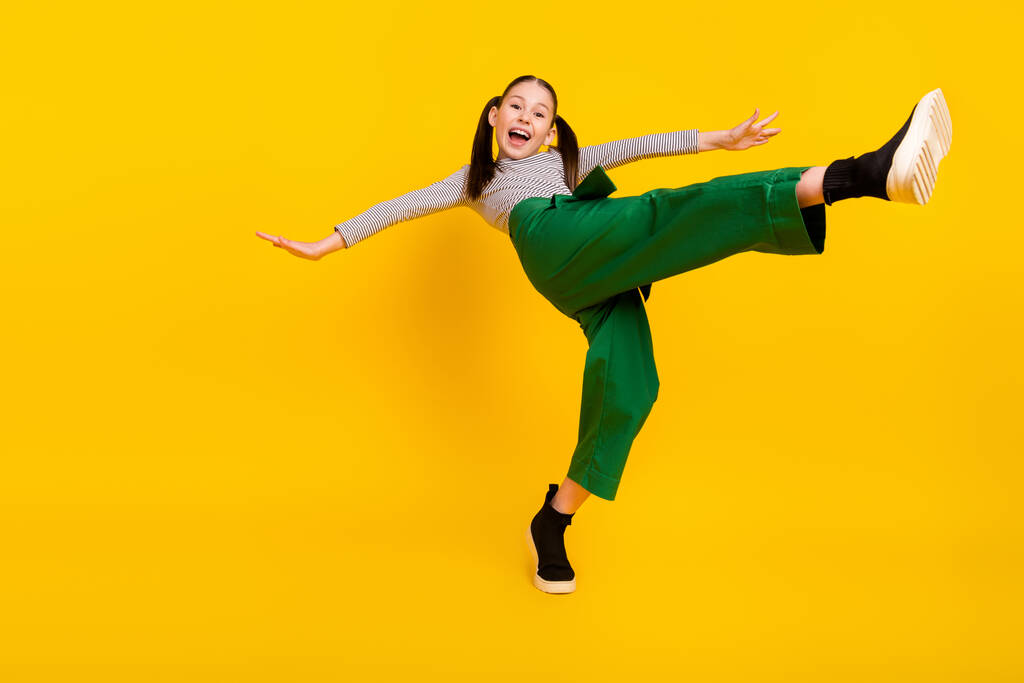 Low angle view full size profile side photo of young excited girl happy positive smile balance isolated over yellow color background - Photo, Image