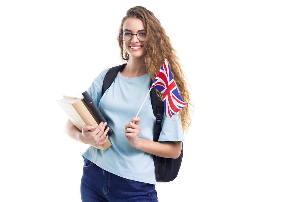 Ευτυχής μαθήτρια με γυαλιά κρατά σημαία του Ηνωμένου Βασιλείου και βιβλία απομονωμένα σε λευκό φόντο - Φωτογραφία, εικόνα