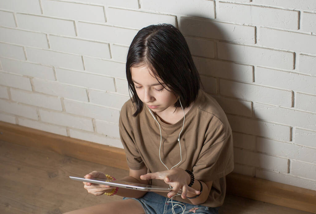 πορτρέτο μιας μελαχρινής έφηβης σε κοντινό πλάνο με ακουστικά και ένα tablet. την έννοια της επικοινωνίας ή της μάθησης onlin - Φωτογραφία, εικόνα