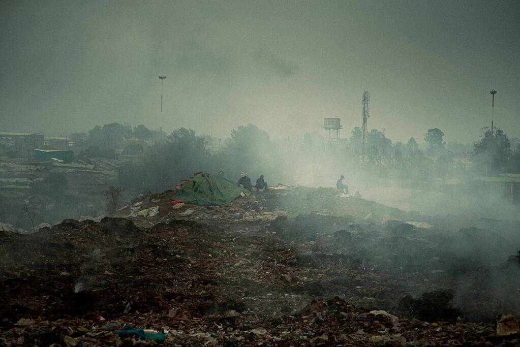 Troje ludzi na wysypisku zanieczyszczonym powietrzem w ponury dzień - Zdjęcie, obraz
