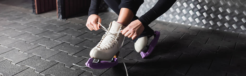 Artistik patinaj ayakkabılarına bağcıklar bağlayan genç bir kadın. - Fotoğraf, Görsel