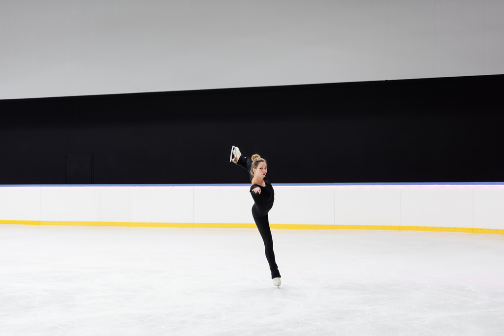 longitud completa de patinador artístico en negro bodysuit patinaje en hielo congelado arena - Foto, Imagen