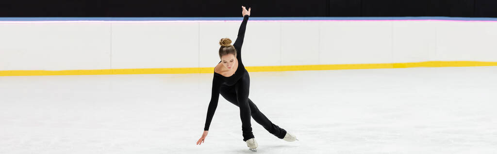 teljes hossza szakmai műkorcsolyázó fekete karosszéria korcsolyázás kinyújtott kézzel jég arénában, banner - Fotó, kép