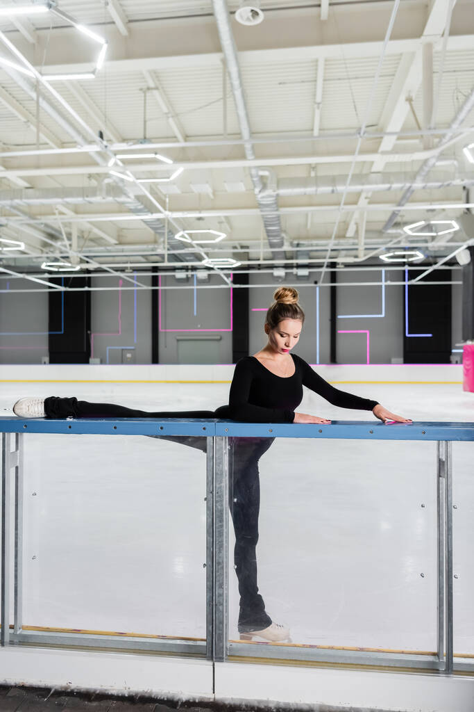 jeune femme en patins artistiques blancs s'étirant près de l'arène de glace - Photo, image
