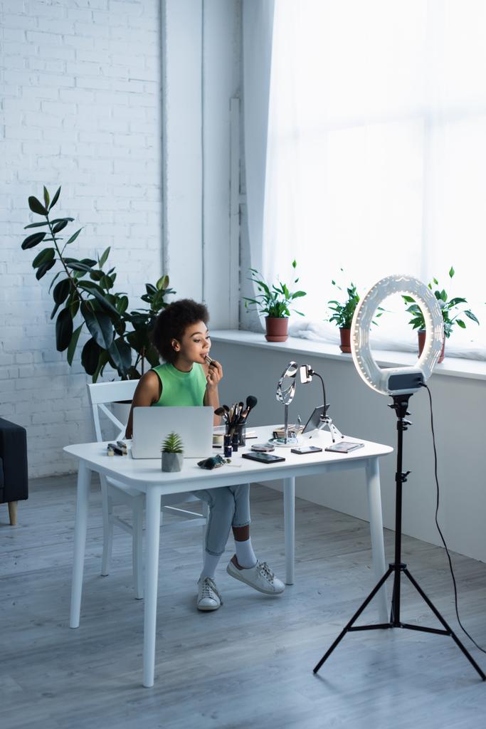 Afrikkalainen amerikkalainen bloggaaja, joka käyttää huulipunaa laitteiden lähellä ja rengasvaloa kotona  - Valokuva, kuva