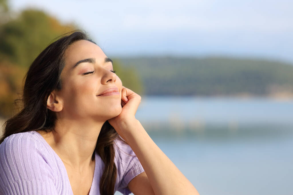Mujer feliz relajándose con los ojos cerrados sentado en la montaña - Foto, imagen