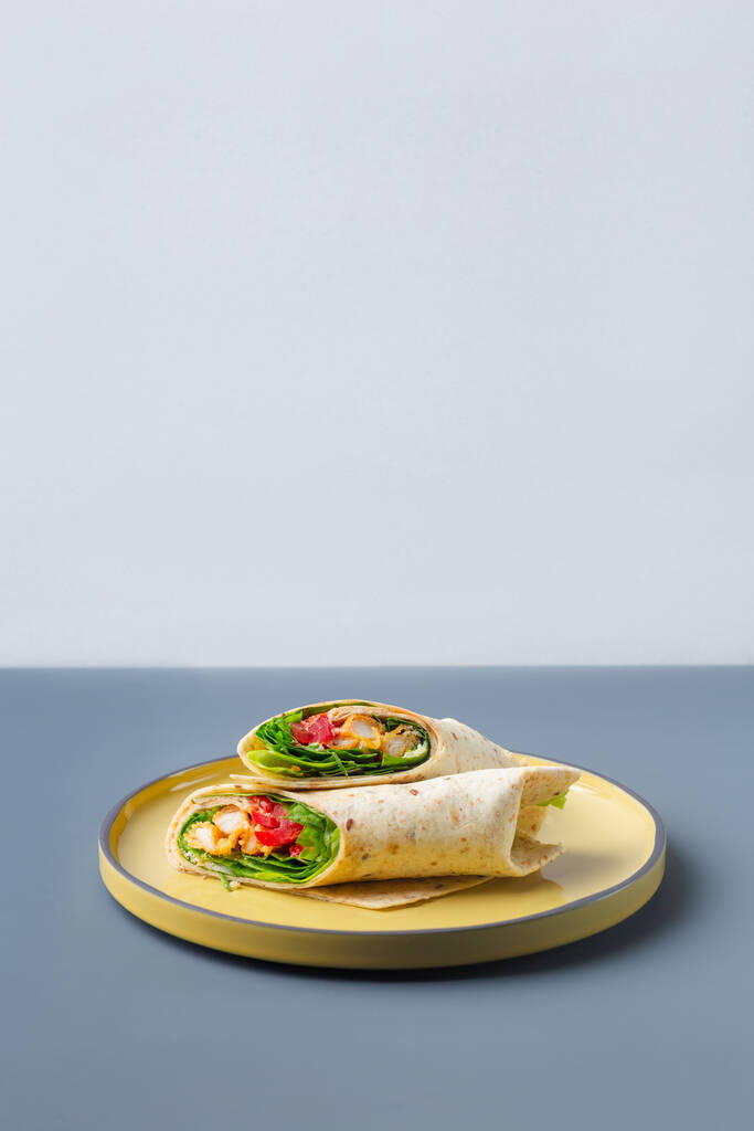 Dvojice čerstvých obalových sendvičů s kuřecím masem a zeleninou na žluté na šedém talíři módní barvy - Fotografie, Obrázek
