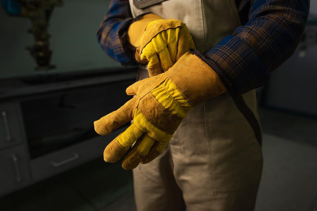 Vista recortada de soldador con guantes en fábrica  - Foto, Imagen