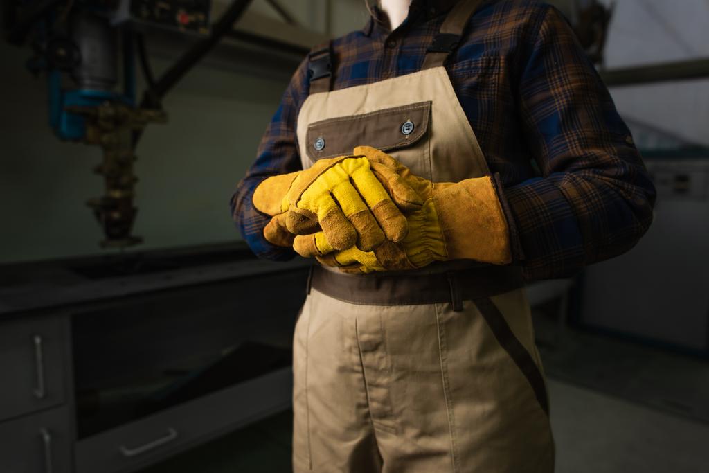 Обрізаний вид зварювальника в рукавичках і комбінезоні на заводі
  - Фото, зображення
