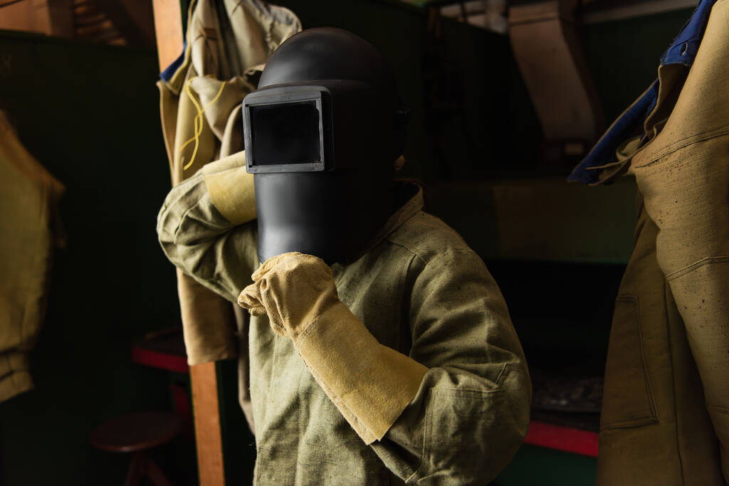 svářečka v rukavicích s ochrannou maskou s hledím v továrně  - Fotografie, Obrázek