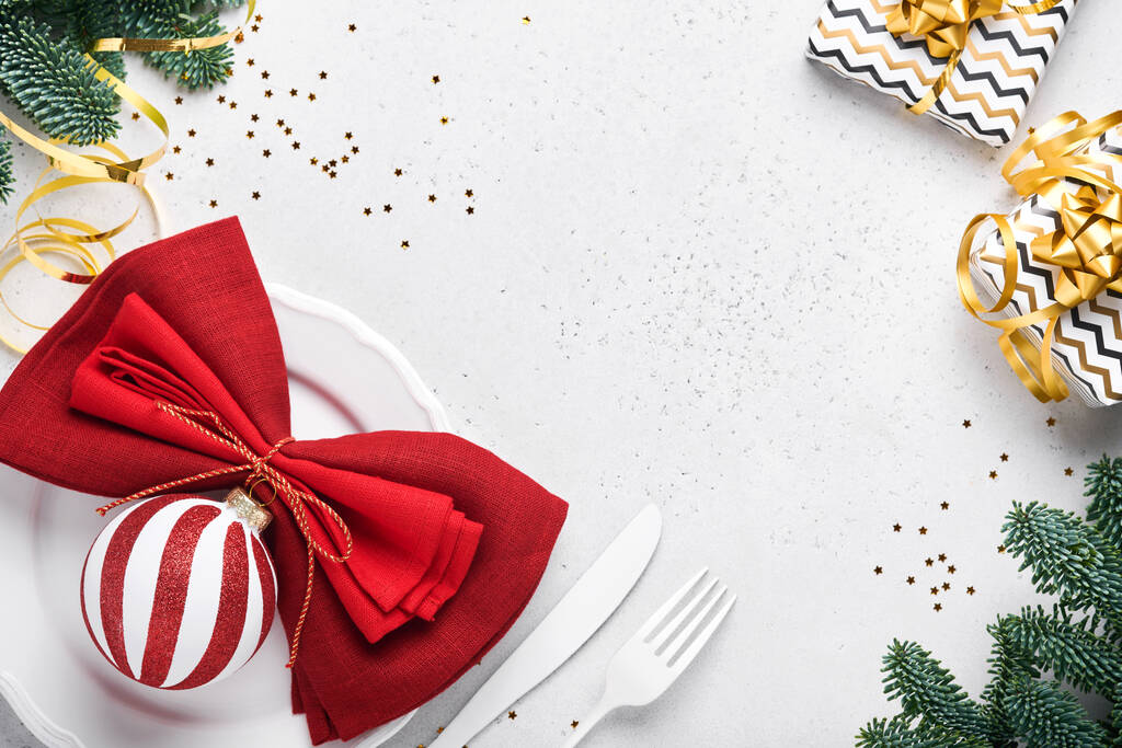Noel masası beyaz renkte, gümüş takımlar, peçete kırmızı renkler, Noel topları, şampanya, beyaz arka planda yeni yıl kutlamaları için bardaklar. Model. - Fotoğraf, Görsel