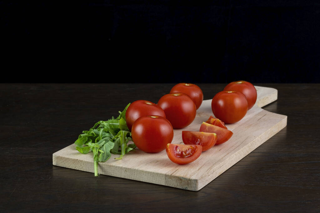 Plan rapproché de tomates rouges sur une table en bois isolée sur fond sombre. - Photo, image