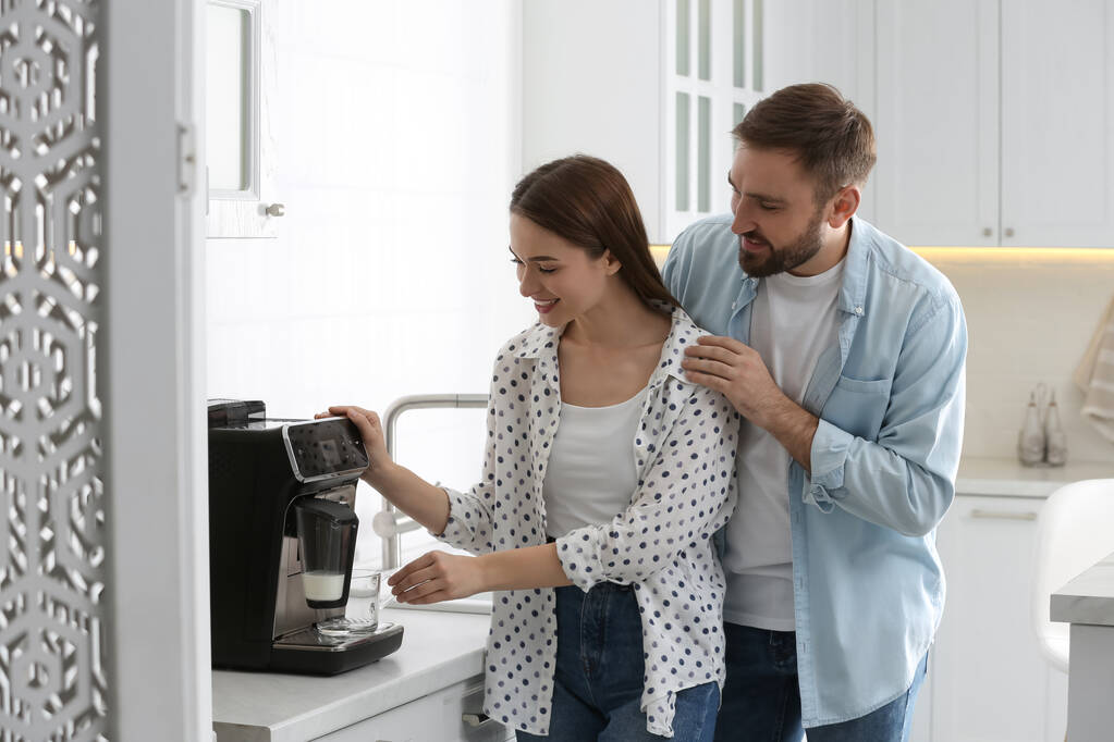 Pareja feliz preparando café aromático fresco con máquina moderna en la cocina - Foto, Imagen