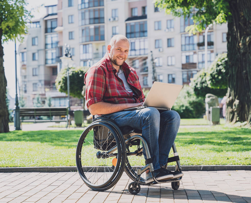 Ελεύθερος επαγγελματίας με σωματική αναπηρία που χρησιμοποιεί αναπηρική καρέκλα που εργάζεται στο πάρκο - Φωτογραφία, εικόνα