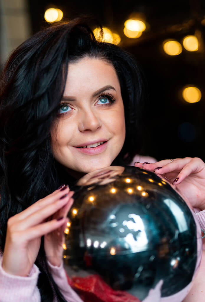 Portret pięknej kobiety z ozdobnym balem. Ładna pani pokazuje świąteczną piłkę w rękach. - Zdjęcie, obraz