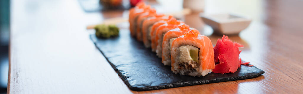 z bliska widok czarnej płyty z pyszne rolki sushi na rozmytym tle, baner - Zdjęcie, obraz