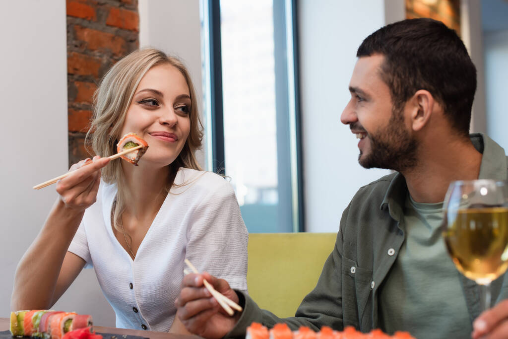 pareja alegre mirándose durante la cena en sushi bar en primer plano borrosa - Foto, Imagen